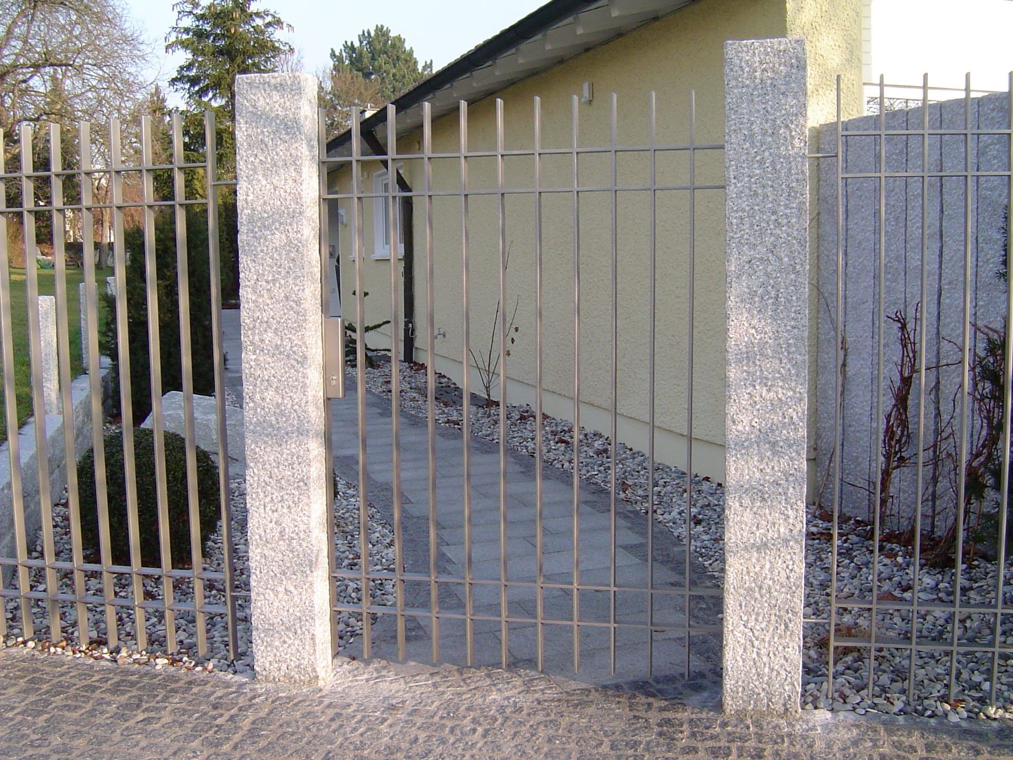 Stahlzaun mit Tor zwischen Granitpfosten, gefertigt von Maier Metallbau
